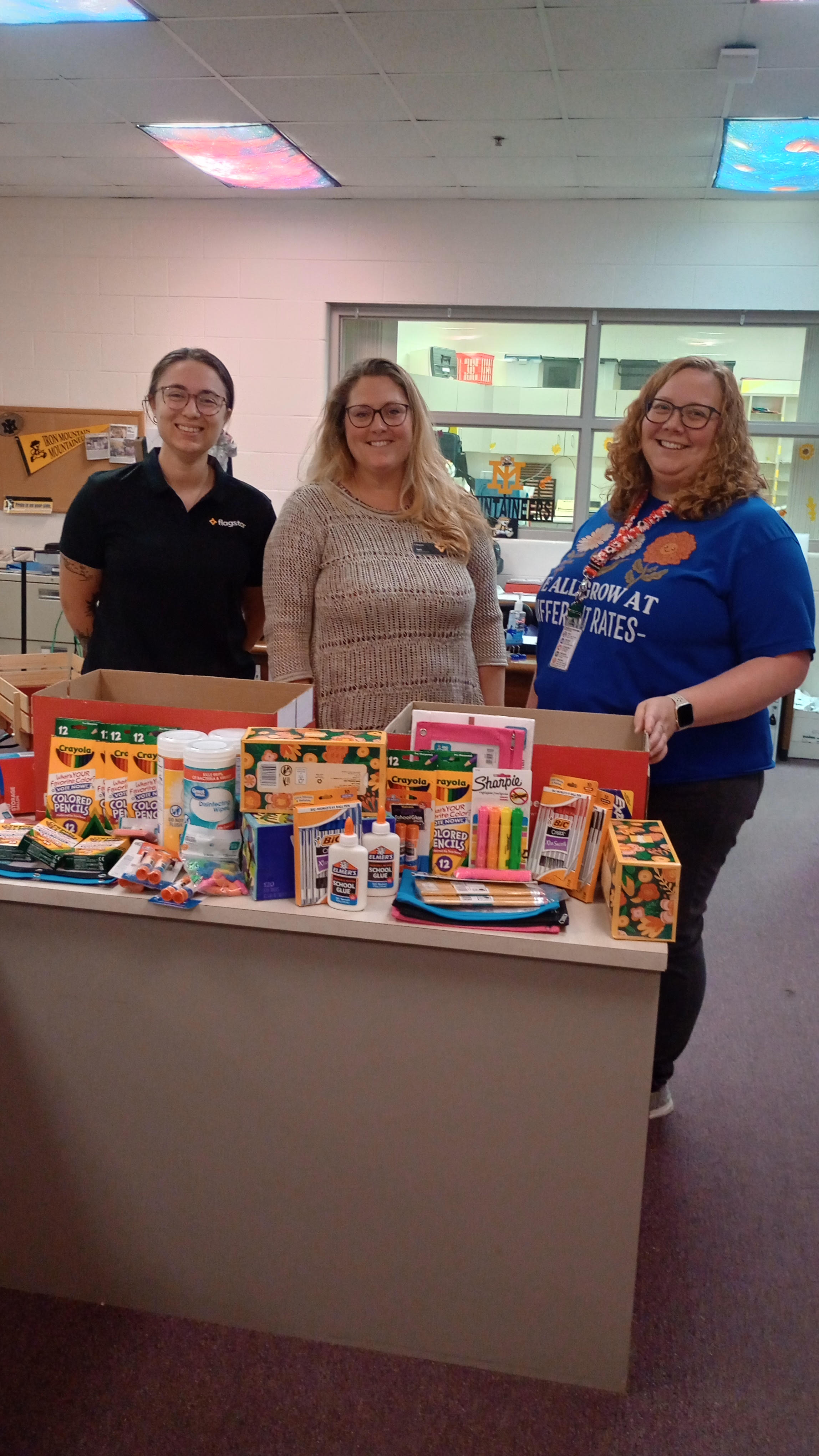 Staff and Flagstar employees stand in front of counter of school supplies